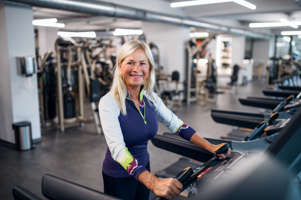 A happy senior woman in gym doing cardio work out exercise.