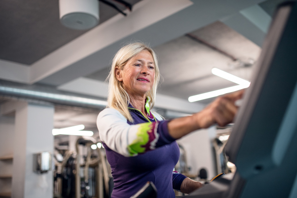 A happy senior woman in gym doing cardio work out exercise.