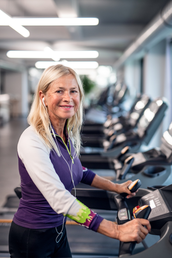 A happy senior woman in gym doing cardio work out exercise.