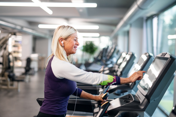 A happy senior woman in gym doing cardio work out exercise.