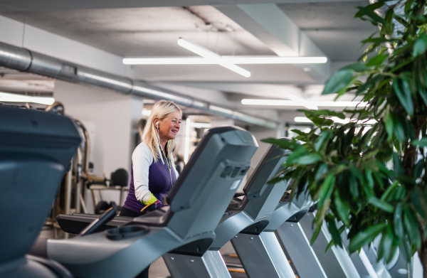 A side view of happy senior woman in gym doing cardio work out exercise.