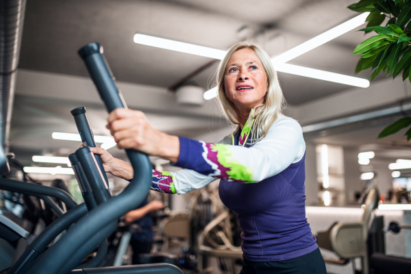 A happy senior woman in gym doing cardio work out exercise.