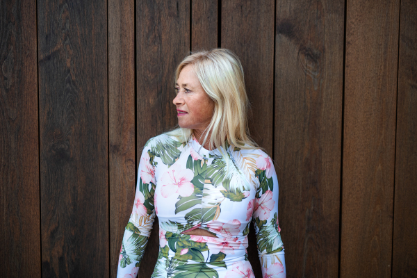 A senior woman standing outdoors, standing against wooden background. Copy space.