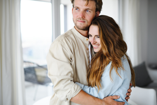 A happy young couple in love indoors at home, hugging.