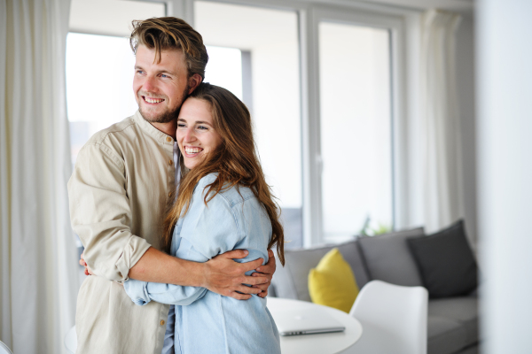 A happy young couple in love indoors at home, hugging.