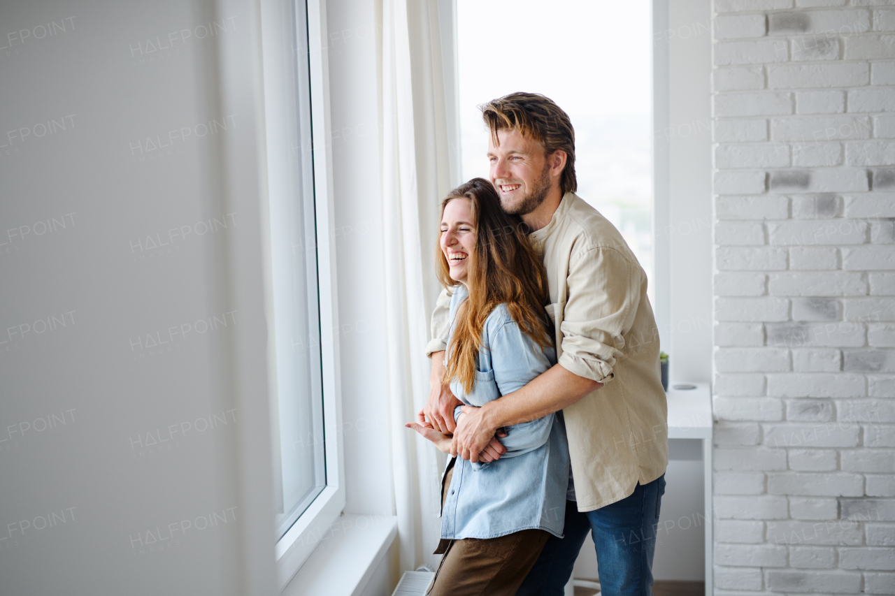 A happy young couple in love indoors at home, hugging and laughing.