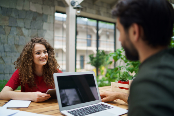 Young man and woman sitting and talking indoors in office, business meeting concept.