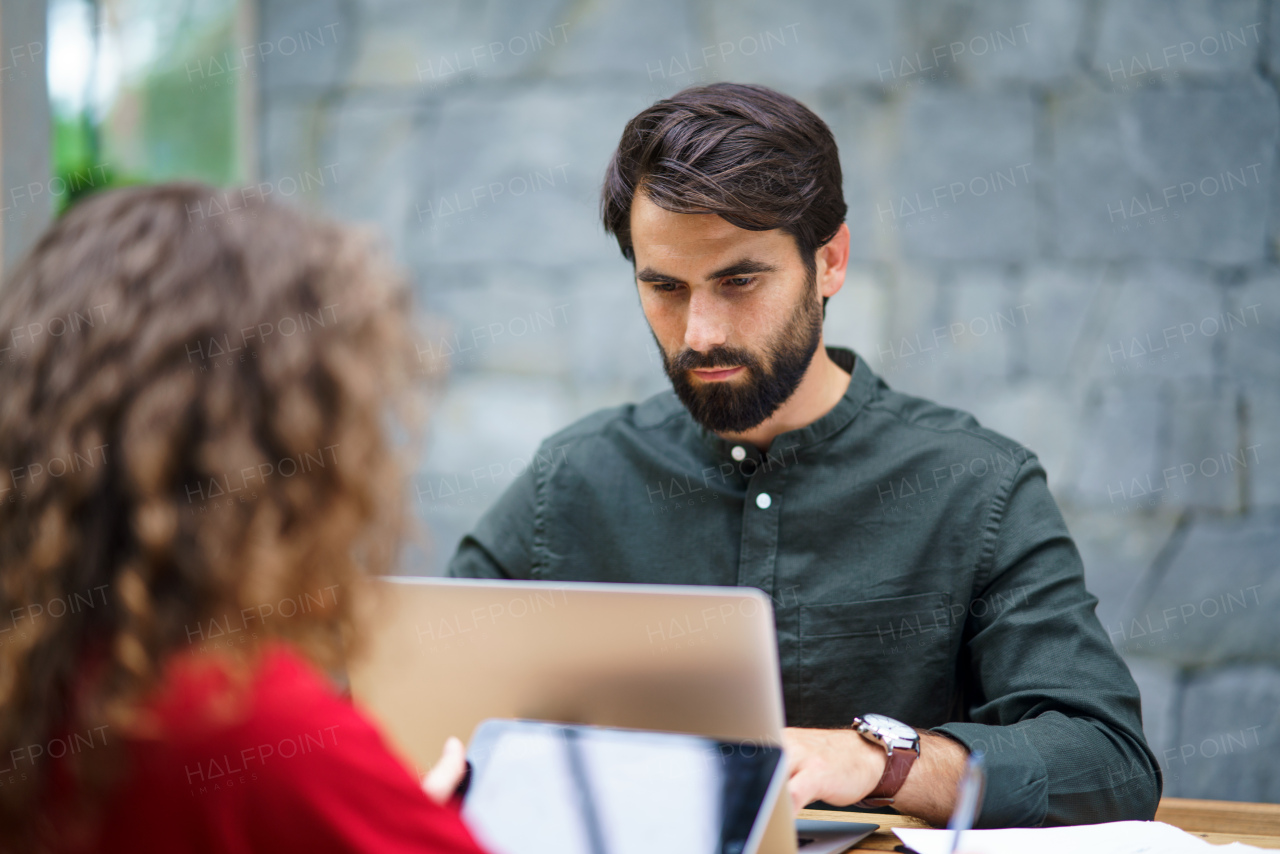 Unrecognizable young man and woman sitting indoors in office, working.