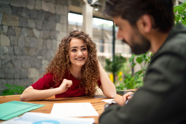 Young man and woman sitting and talking indoors in office, business meeting concept.