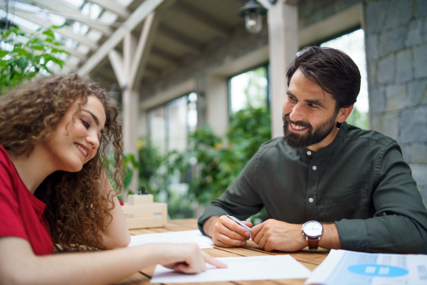 Young man and woman sitting and talking indoors in office, business meeting concept.