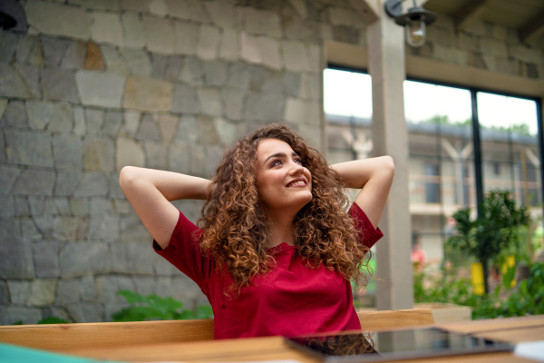 Portrait of young woman sitting indoors in office, resting.