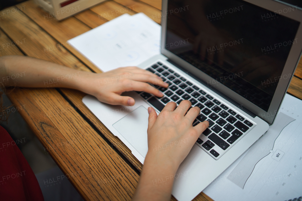 Top view of unrecognizable woman with laptop sitting indoors in office, working.