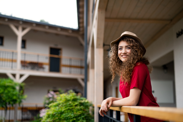 Happy young woman standing outdoors by hotel on holiday, relaxing.