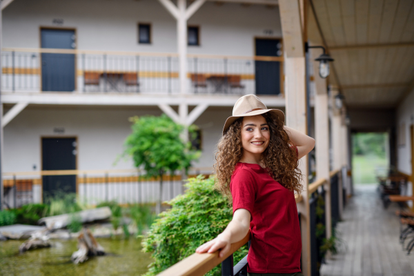 Happy young woman standing outdoors by hotel on holiday, relaxing.