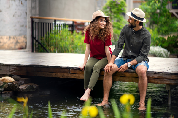 Happy young couple sitting outdoors by lake hotel on holiday, having fun.