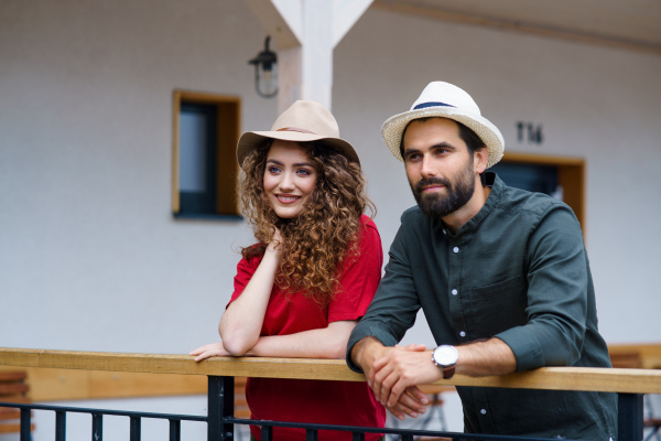 Portrait of young couple standing outdoors by hotel on holiday, relaxing.