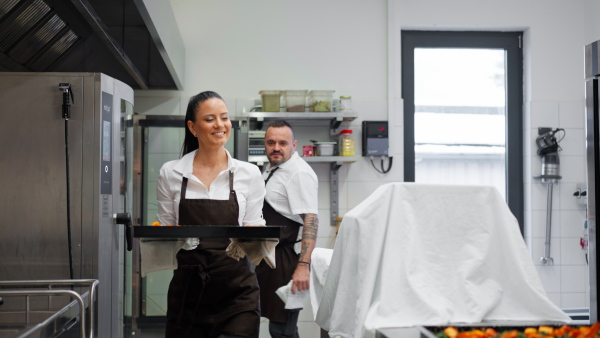 A chef and cook working on their dishes indoors in restaurant kitchen.