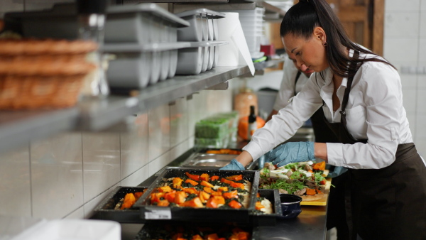 A chef and cook working on their dishes indoors in restaurant kitchen.