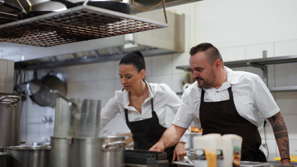 Professional chefs preparing the burgers indoors in restaurant kitchen.