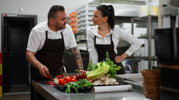 A chef teaching how to cook, cutting vegetables indoors in commercial kitchen.