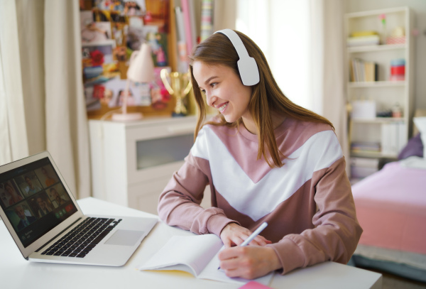 Happy young woman with headphones and laptop, online business call concept.