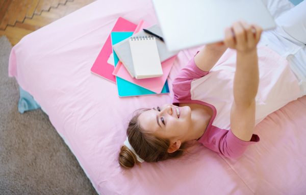 Young girl with tablet sitting and relaxing on bed, quarantine concept.