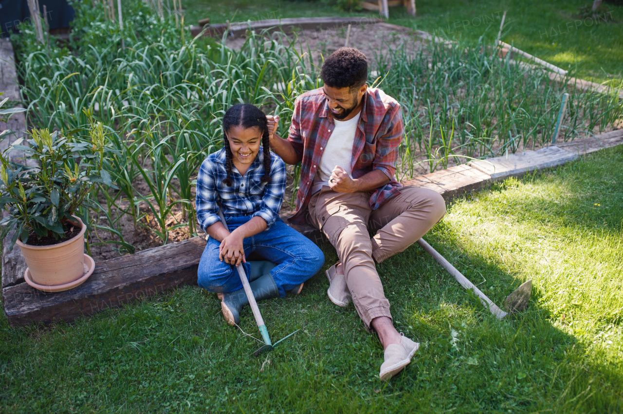 Happy young father with small daughter working outdoors in backyard, a gardening concept.