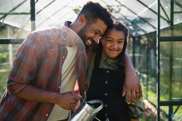 A happy young brother with small sister having fun outdoors in backyard, gardening and greenhouse concept.