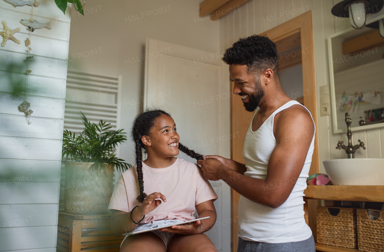 A happy young man with small sister indoors at home, having fun in bathroom.