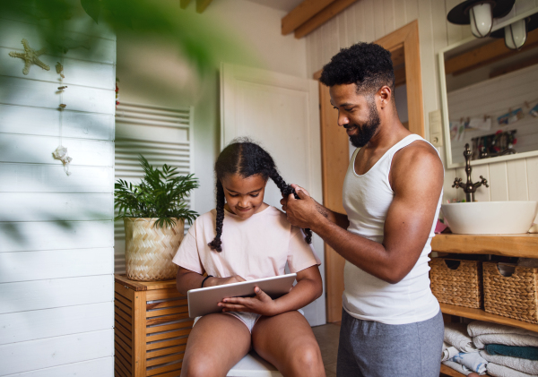 A happy young man with small sister indoors at home, having fun in bathroom.