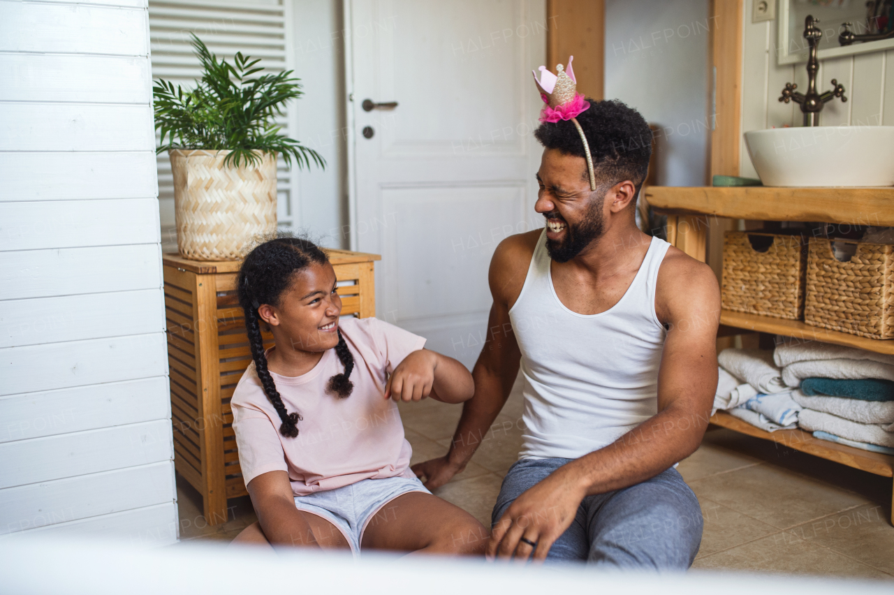 A happy young man with small sister indoors at home, having fun in bathroom.