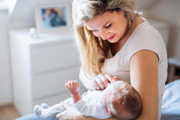 A beautiful young mother holding a newborn baby at home.