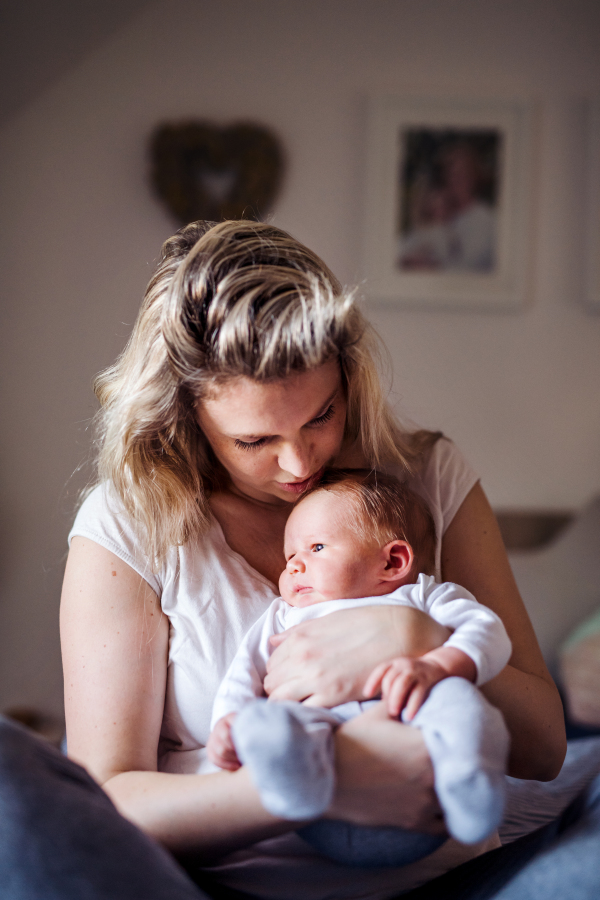 A beautiful young mother holding a newborn baby at home.