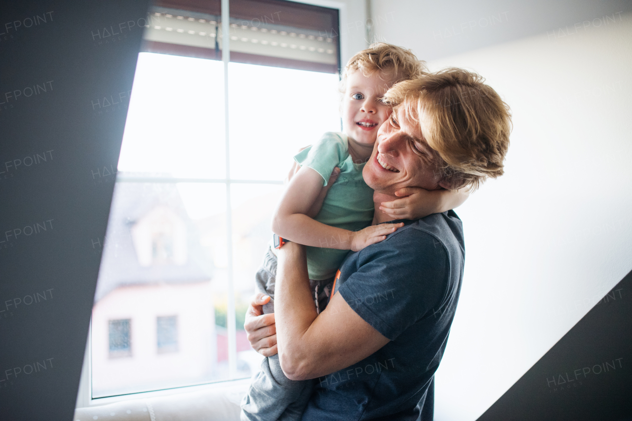 A happy father holding a toddler son at home.