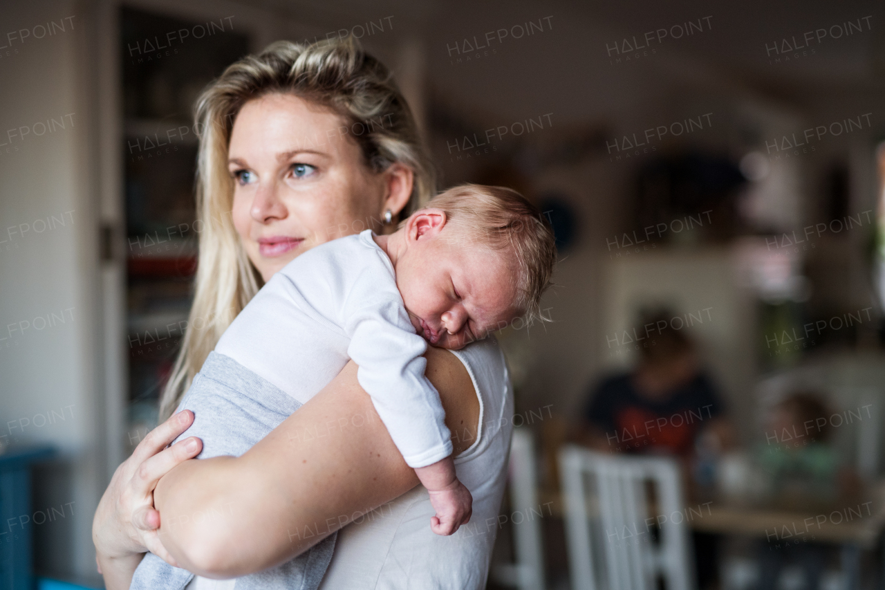 A beautiful young mother holding a sleeping newborn baby at home. Copy space.