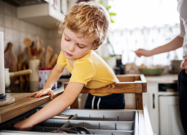 A happy small toddler boy standing in a kitchen at home.