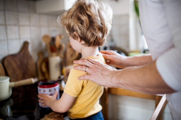 A young father with a toddler son spending time in a kitchen at home.