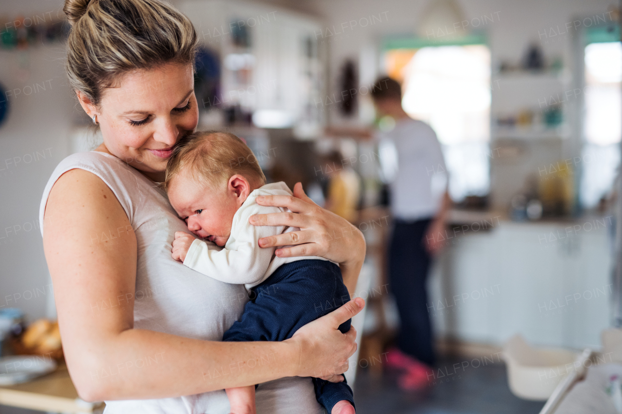 A beautiful young mother holding a newborn baby at home.