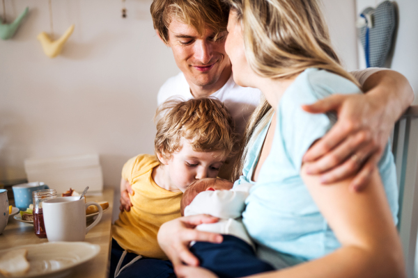 Young parents with a newborn baby and small toddler son at home.