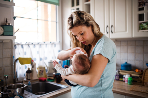 A beautiful young mother holding a newborn baby at home.