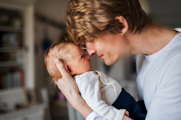 A happy young father with a newborn baby son at home.