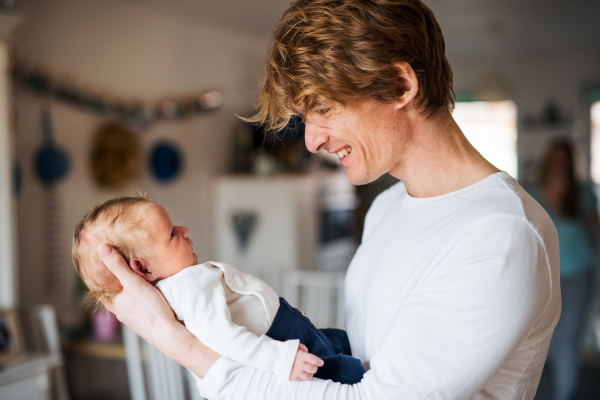 A close -up of young father holding a newborn baby at home.