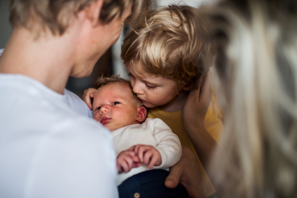 Young parents with a newborn baby and small toddler son at home, a close-up.