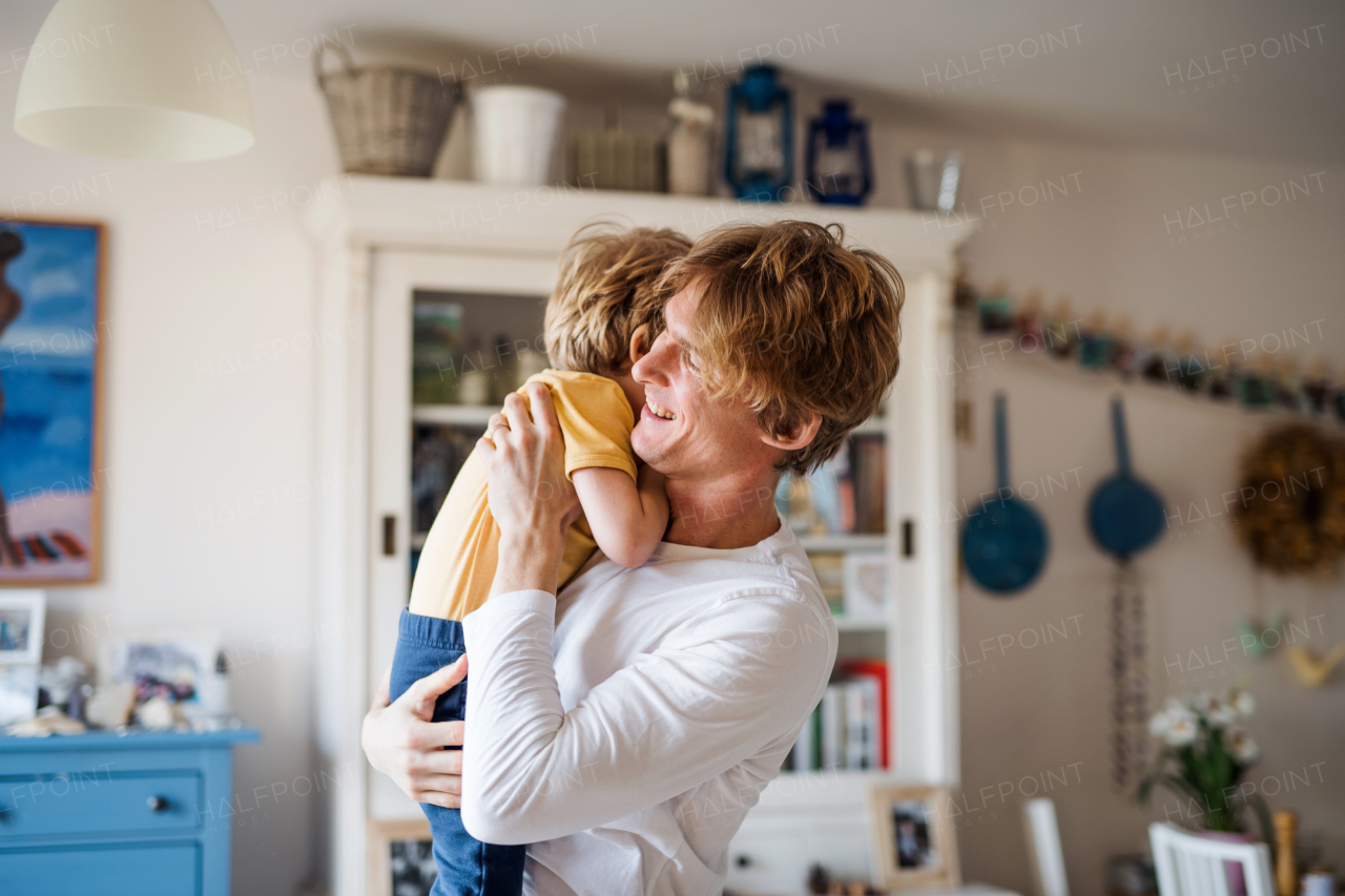 A happy father holding a toddler son at home.