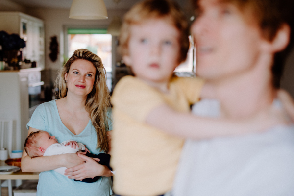 Young parents with a newborn baby and small toddler son at home.