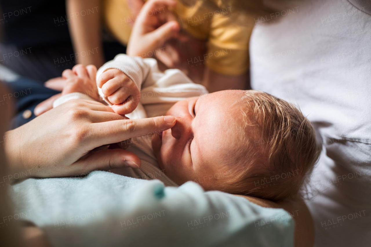 A midsection of parents with newborn baby and small toddler son at home.