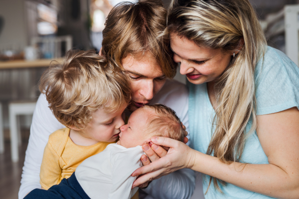 Young parents with a newborn baby and small toddler son at home.