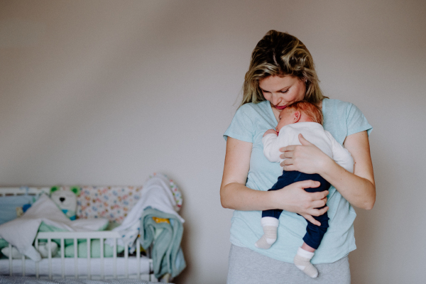 A beautiful young mother holding a newborn baby at home.