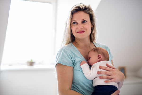 A beautiful young mother holding a newborn baby at home.