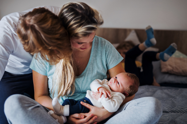 Young parents with a newborn baby and small toddler son at home.